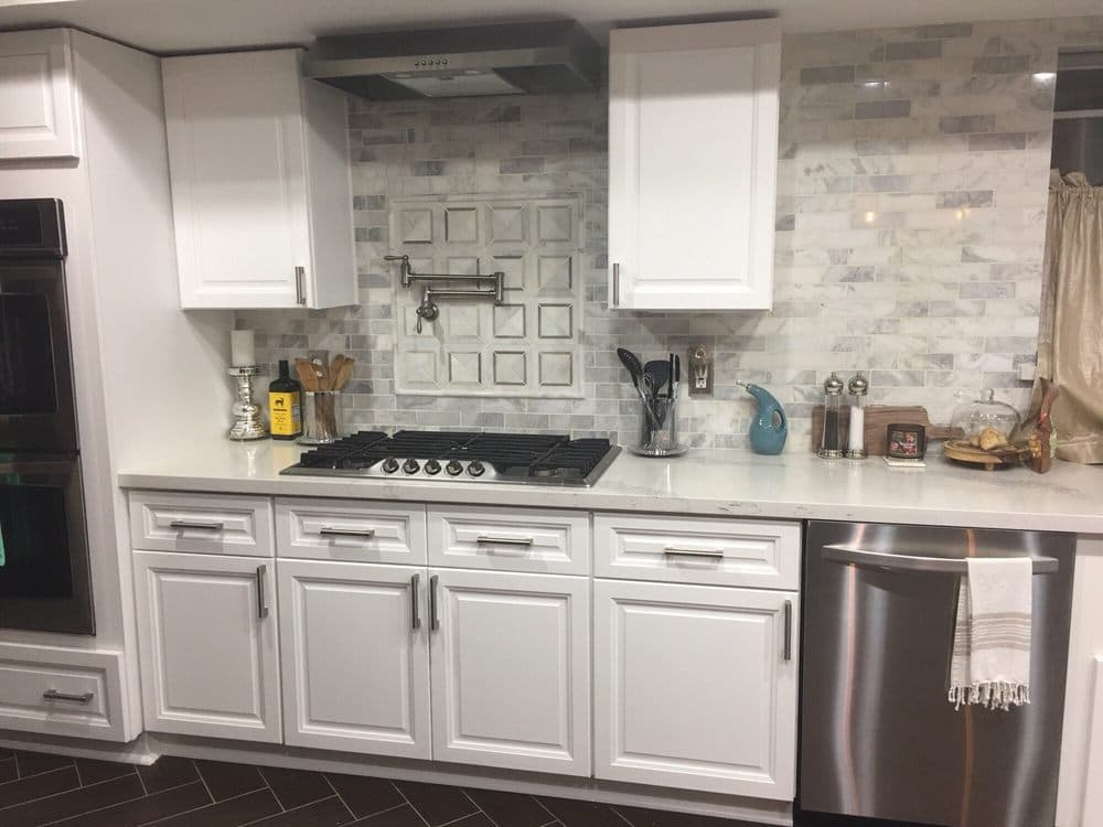 White quartz countertop with marble subway tile backsplash and white shaker cabinets