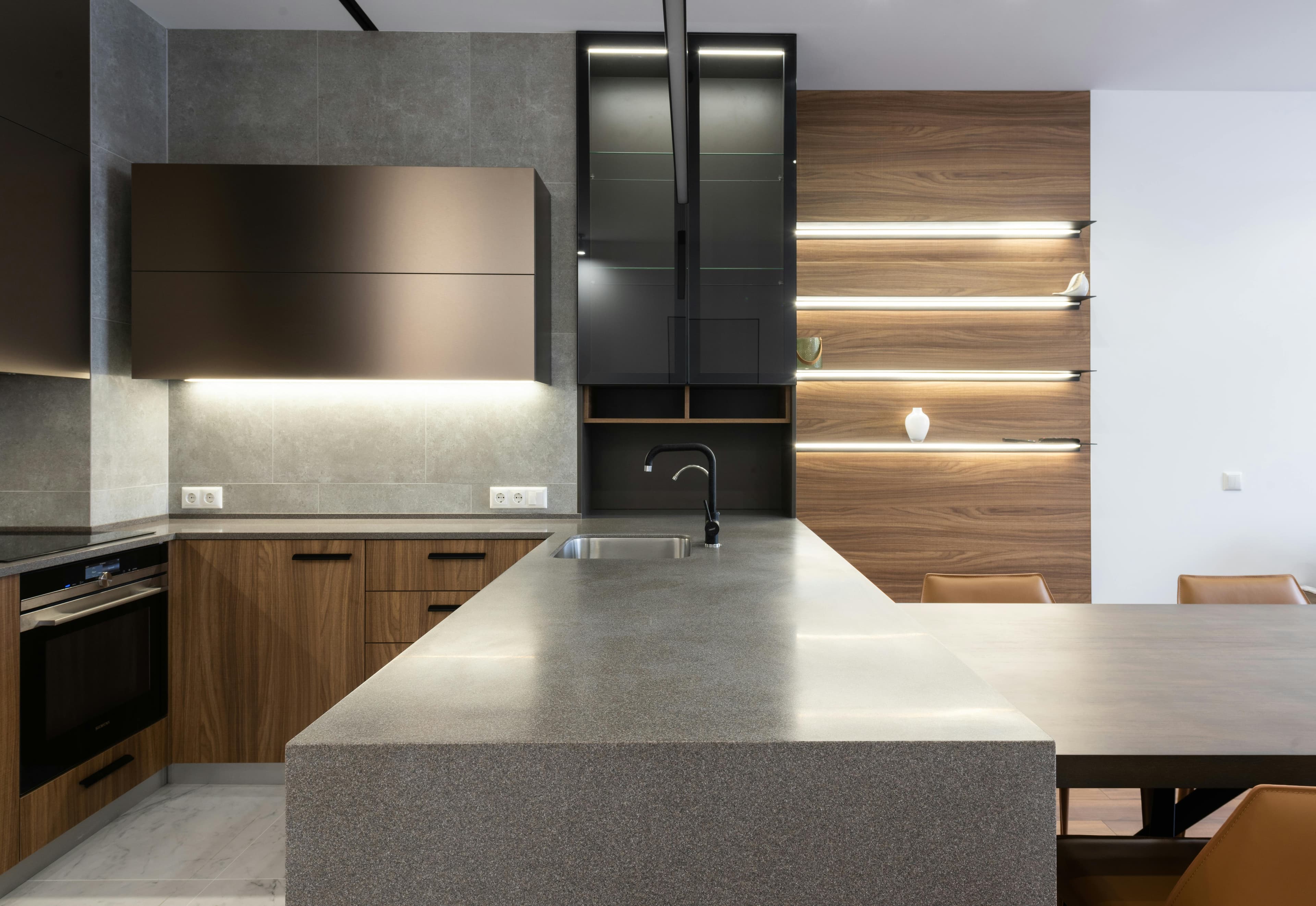 Modern gray quartz island countertop with walnut and glass cabinets